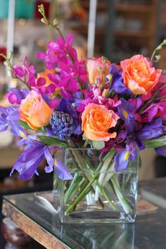 a glass vase filled with purple and orange flowers