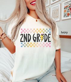 a woman sitting on top of a bed wearing a t - shirt that says 2nd grade