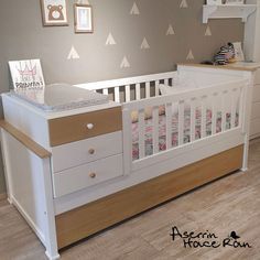 a baby's room with a crib, dresser and wall decals on the walls