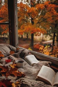 an open book sitting on top of a window sill next to a cup of coffee