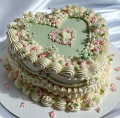 a heart shaped cake on a plate with pink and green flowers around the edges that spell love