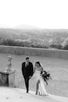 a bride and groom are walking down the sidewalk together in black and white photo by their wedding photographer