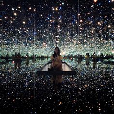 a woman is sitting on a bench in the middle of a room filled with lights