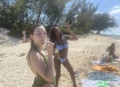 two women standing on the beach eating food