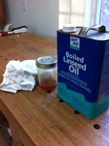 a bottle of oil sitting on top of a wooden table next to a canister