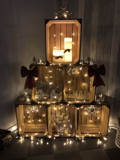 a christmas tree made out of wooden crates with lights around it and decorations on top