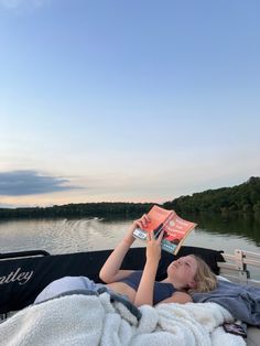 a woman laying in a boat reading a book