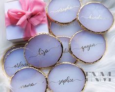 six personalized glass coasters with the names of bride and groom on them next to a pink bow