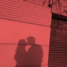 the shadow of a man and woman standing next to each other in front of a building