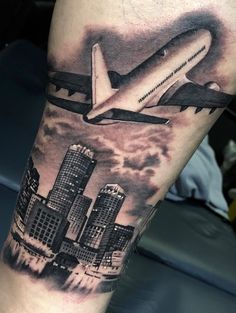 an airplane is flying over the city in this tattoo