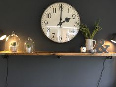 a clock is on the wall above a shelf with flowers and candles in vases