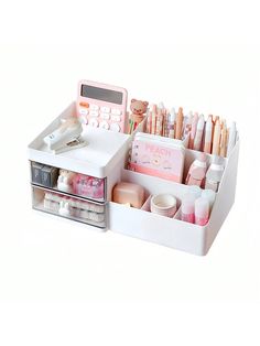 a white desk organizer with pink and white items in the drawer on top of it