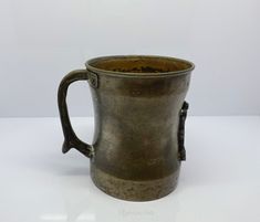 an old metal cup sitting on top of a white table