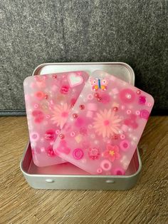 two pink plastic trays with flowers and hearts on them sitting on a wooden table