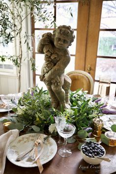 the table is set with plates, silverware and an angel figurine