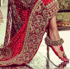 a woman's feet in high heels and red dress with gold jewelry on them