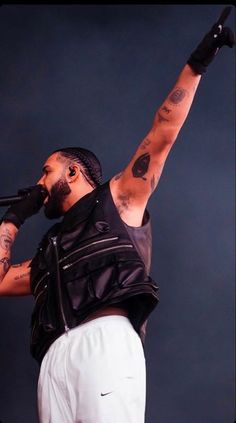 a man with his arms in the air while singing into a microphone on stage at a concert