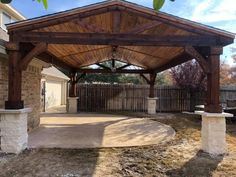 an outdoor covered patio area in the middle of a yard with brick pillars and columns