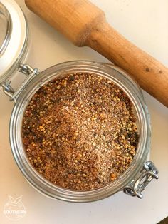 a metal bowl filled with spices next to a wooden rolling pin on top of a table