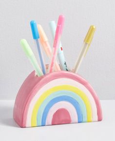 a cup with toothbrushes in it and a rainbow shaped container on the side