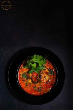 a black bowl filled with food and garnished with cilantro, parsley