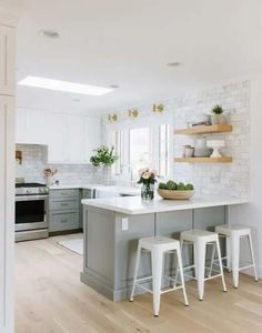 a white and gray kitchen with two stools