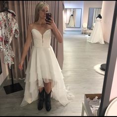 a woman taking a selfie in front of a mirror wearing a white wedding dress