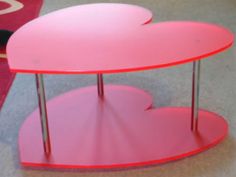 a pink table sitting on top of a carpeted floor next to a red rug