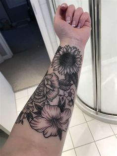 a woman's arm with a sunflower and flowers tattoo on the left wrist