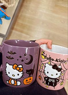 two hello kitty coffee mugs sitting next to each other