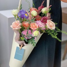 a woman holding a white bag with flowers in it and a tag on the handle