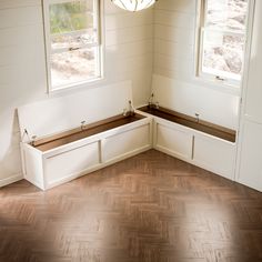 an empty room with two windows and some benches in the corner on the far side