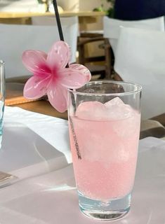 two glasses filled with water and ice sitting on top of a white tablecloth covered table