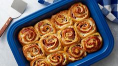 a blue casserole dish filled with cinnamon rolls