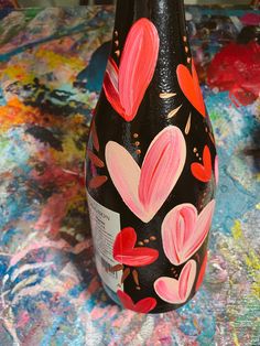 a painted wine bottle with hearts on it