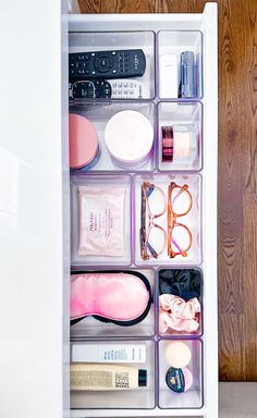 an organized drawer filled with personal items on top of a wooden floor next to a wall