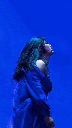 a woman with green hair is standing in front of a blue background and looking up