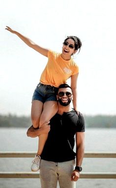 a man is holding a woman on his shoulders while she holds her up in the air