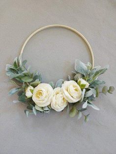 a wreath with white roses and greenery on a gray background for a wedding or bridal party decoration