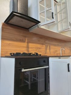 a stove top oven sitting inside of a kitchen next to white cupboards and cabinets