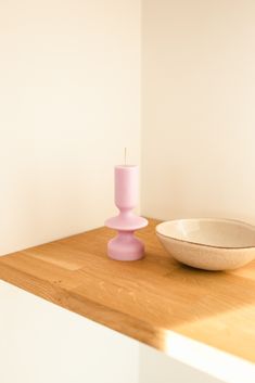 a bowl and candle sit on a counter in front of a wall with white walls