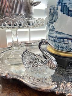 two glass dishes sitting on top of a wooden table next to a silver platter