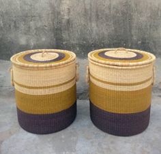 two woven baskets sitting next to each other on the cement floor in front of a wall