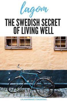 a blue bicycle parked in front of a building with the words lagon the swedish secret of living well