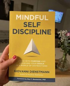 the book mindful self discipline is being held up by a woman's hand