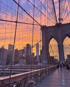 people walking across the brooklyn bridge at sunset