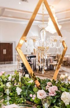 a table topped with flowers and greenery next to a chandelier