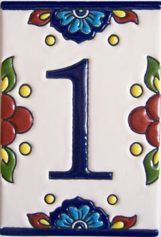 the number one is decorated with blue and red flowers on white tiles, as well as green leaves