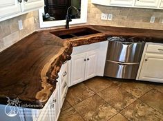 a wooden counter top in a kitchen with white cabinets and stainless steel dishwasher