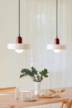 a wooden table topped with a white vase filled with flowers next to a hanging light